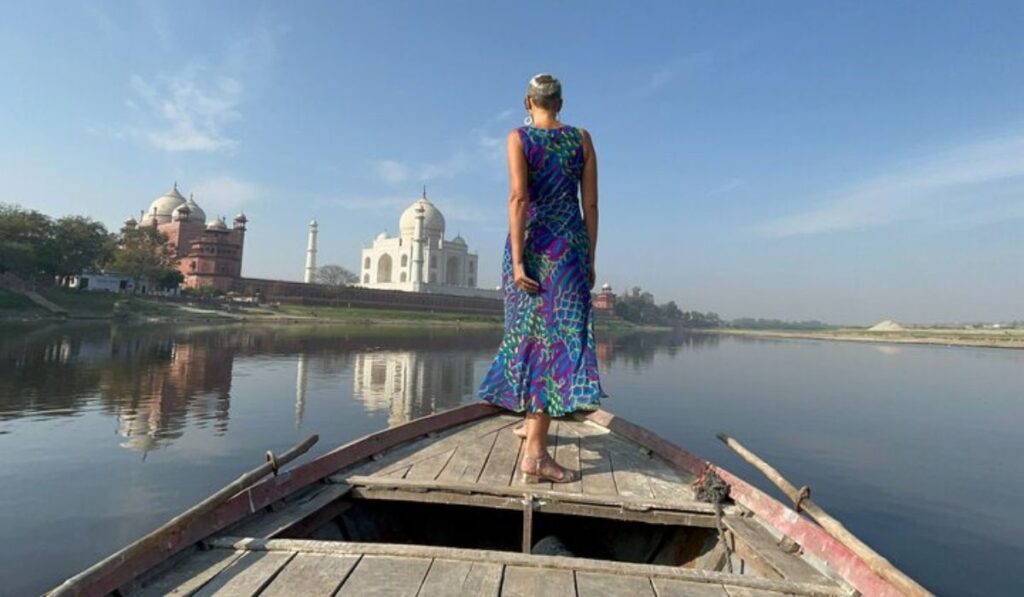 Woman standing on a boat with scenic Taj Mahal river view near Mehtab Bagh.